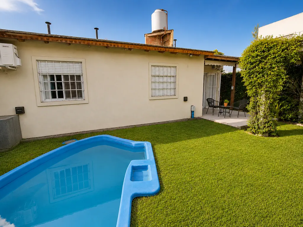 Pileta en el jardín con césped y vista del contrafrente de la casa